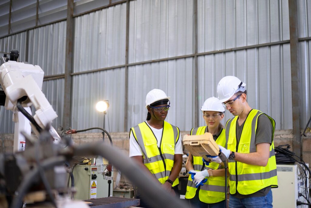 Blue collar workers are working with welding robot arm.